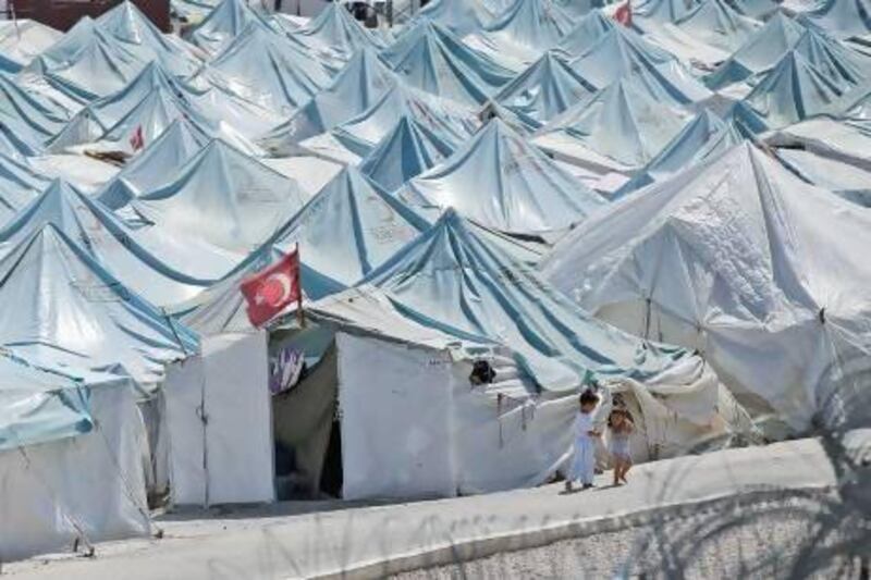 Children walk past Syrian refugees’ tents at a camp in Yayladagi, Turkey.