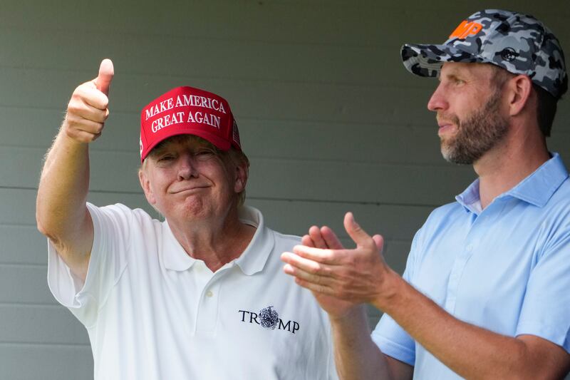 Mr Trump gives a thumbs up to fans in the crowd as he stands with his son Eric Trump. AP