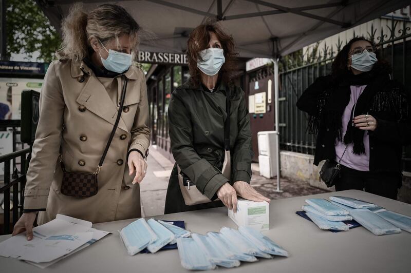 Volunteers distribute face masks and leaflets to commuters outside a metro station in Vincennes on the outskirts of the French capital Paris, on April 30, 2020, on the 45th day of a lockdown in France aimed at curbing the spread of the COVID-19 disease, caused by the novel coronavirus. French Prime Minister announced on April 28 that face masks will be compulsory on public transport as France will begin a gradual but "risky" return to normality on May 11. / AFP / Philippe LOPEZ
