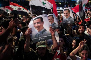 FILE - In this May 27, 2021 file photo, Syrian President Bashar Assad supporters hold up national flags and pictures of Assad as they celebrate at Omayyad Square, in Damascus, Syria.  Jordan’s King Abdullah received a call from Syrian President Bashar Assad, Sunday, Oct.  3, 2021, the first between the two leaders after a decade of strained relations over Syria's civil war.  (AP Photo / Hassan Ammar, File)