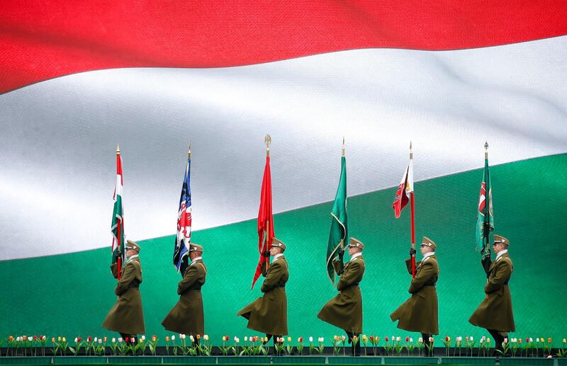 Hungarian soldiers in Budapest march, backdropped by a large display showing Hungary's national flag during a ceremony celebrating the Hungarian national day. Darko Vojinovic / AP Photo