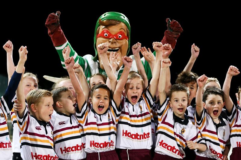 Team mascot Turbo Man of Manawatu poses with children in Palmerston North, New Zealand. Hagen Hopkins / Getty Images