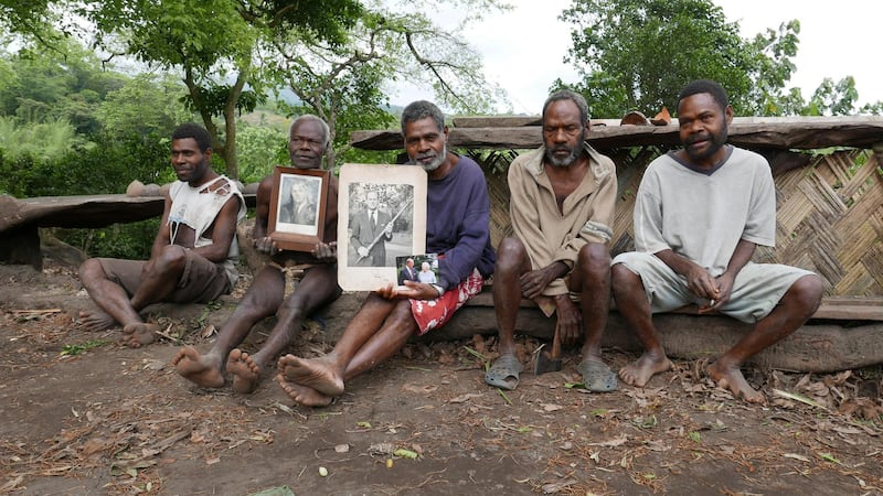 Village chief Jack Malia, centre, holds a picture of Prince Philip in Younanen. Villagers pray to the prince, asking for his blessing on their crops. Reuters