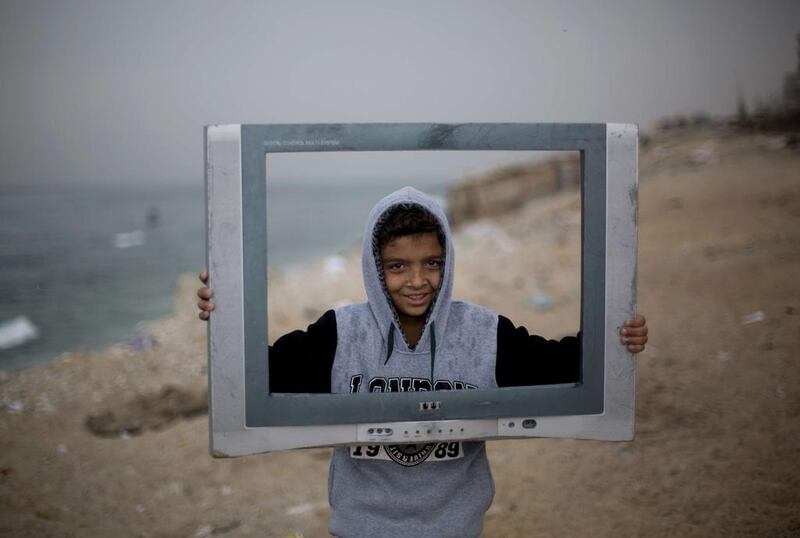 A Palestinian boy poses inside the frame of a broken television at the Al Shatee refugee camp in Gaza City. Mohammed Abed / AFP Photo