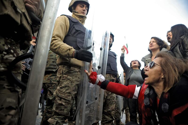 A Lebanese anti-government protester grabs the shield of a Lebanese army soldier as she blocks a road leading to the parliament in the capital Beirut's downtown district.  AFP