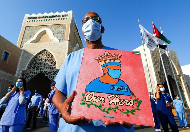 Abu Dhabi, United Arab Emirates, June 21, 2020.   
  A healthcare worker from Sheikh Khalifa Medical City holds up a Hero poster of Dr. Salah.
Victor Besa  / The National
Section:  NA
Reporter: