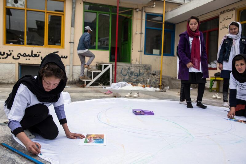 Young activists write climate change messages onto a while sheet in Kabul. 
