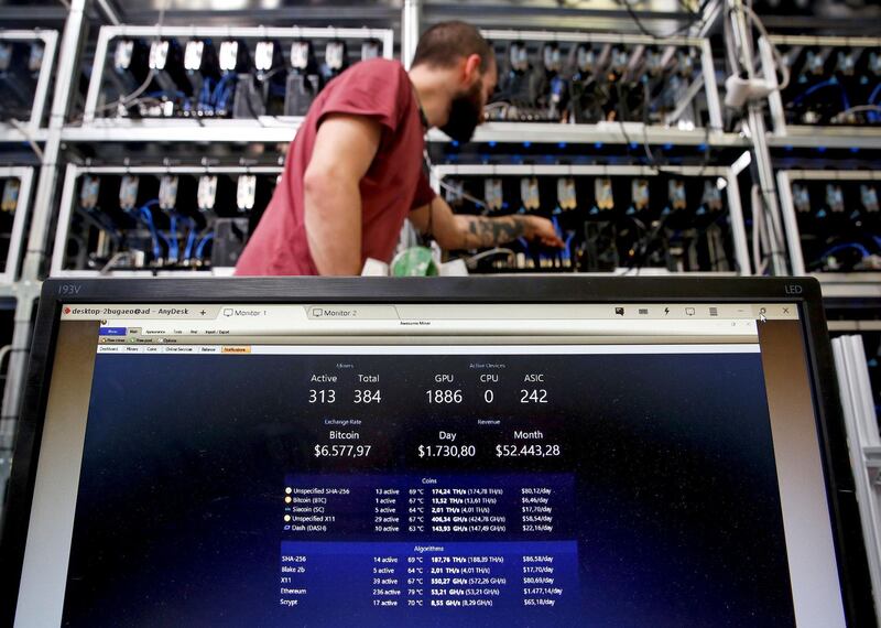 FILE PHOTO: An employee works on Bitcoin mining computer as a PC screen shows the fluctuations in Bitcoin exchange rates at Bitminer Factory in Florence, Italy, April 6, 2018. Picture taken April 6, 2018. REUTERS/Alessandro Bianchi/File Photo