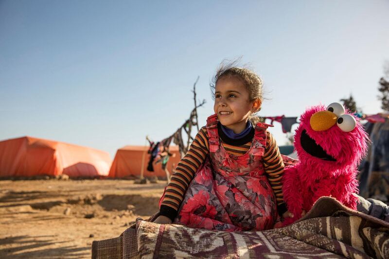 In this Feb. 2017 photo Photo courtesy of Ryan Heffernan and Sesame Workshop, a young girl engages with Sesame Street caricature Elmo at an informal tented settlement near Mafraq,Jordan. The John D. and Catherine T. MacArthur Foundation announced Wednesday, Dec. 20, 2017, that Sesame Workshop and International Rescue Committee will get a $100 million grant from a Chicago-based foundation. for a joint program that will include home visits focused on early learning, child development centers and a local version of "Sesame Street." (Ryan Heffernan/Sesame Workshop via AP)