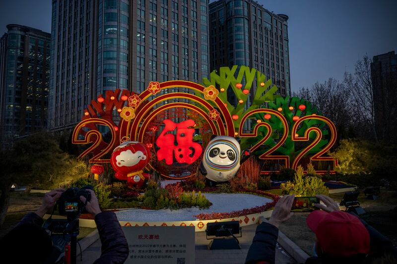 People take pictures of a display for the Beijing 2022 Winter Olympics and Paralympics. Getty