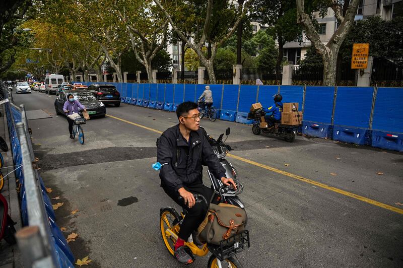 People ride bicycles next to barricades in Shanghai on November 28, 2022, a day after protests against China's Covid-19 restrictions.  AFP