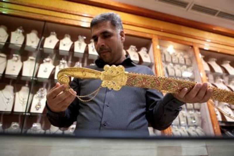 Habibullah, an Iranian shopkeeper at Baniyas Jewelry, shows off his Dh 250,000 khangar on Thursday, Jan. 19, 2012, at the Madinat Zayed Gold Souq in Abu Dhabi.  The gold sword too will have to be stamped after the new law that requires so is out. (Silvia Razgova/The National)
