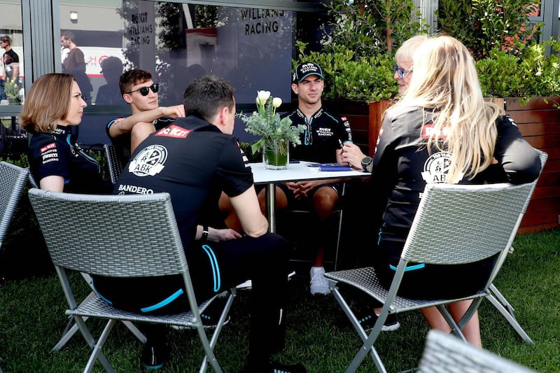 Williams drivers George Russell and Nicholas Latifi and crew sit around a table at Albert Park.