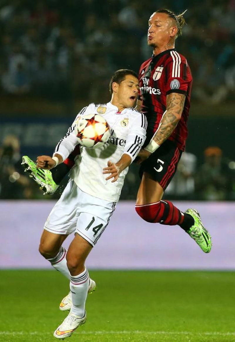 Real Madrid’s Javier Hernandez (L) vies for the ball against AC Milan’s player Philippe Mexes during their friendly football match on December 30, 2014 at the Sevens Stadium in Dubai. AFP PHOTO / MARWAN NAAMANI