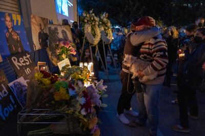 People hug near a memorial table during a candlelight vigil for cinematographer Halyna Hutchins in Burbank, California. AFP
