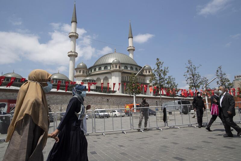 People walk in front of the newly built Taksim Mosque at the Taksim Square during the opening ceremony of the mosque. EPA