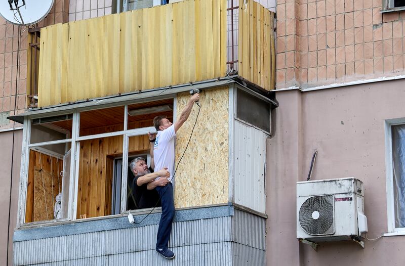 Two men conduct repair works in a flat after a missile strike hit the Piatykhatky neighborhood of Kharkiv, in north-eastern Ukraine.  EPA 