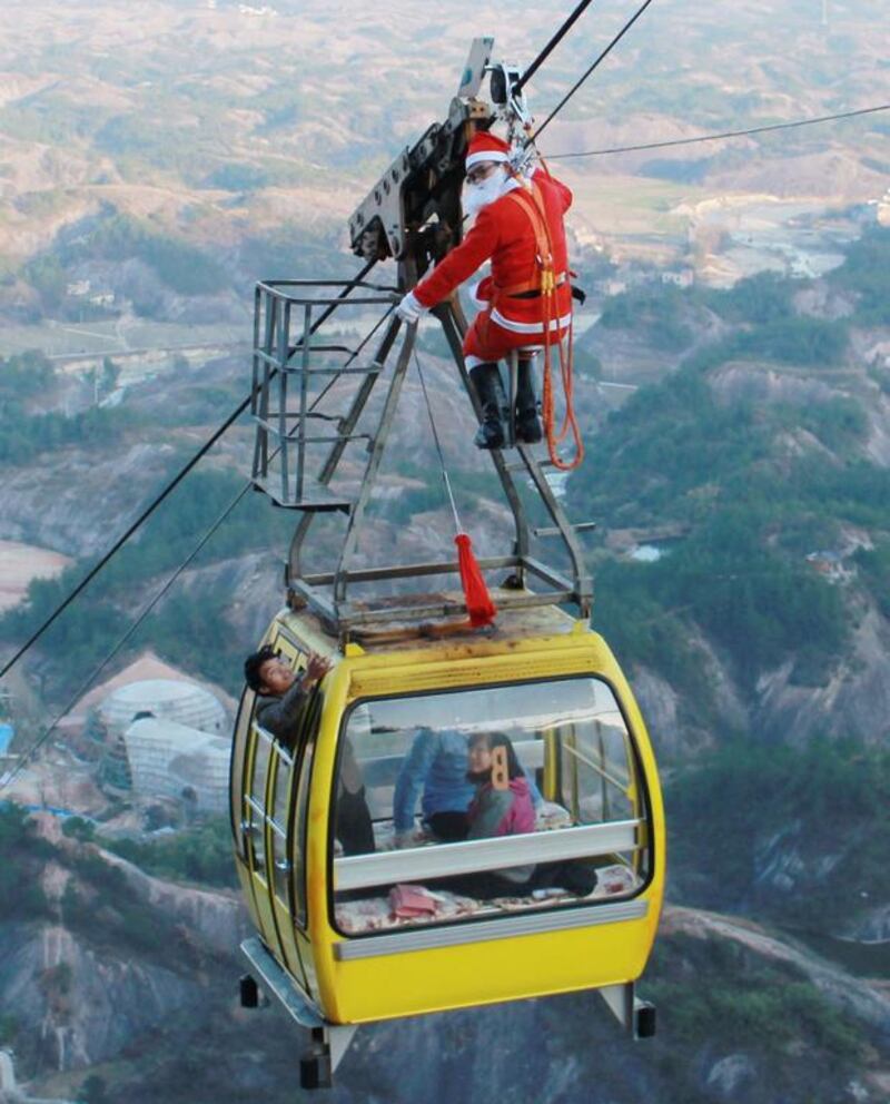 A man dressed up as Santa Claus hanging from a cableway as he delivers Christmas gifts to visitors in a gondola at a scenic area in Yueyang, central China’s Hunan province. Staff of the scenic area expect to attract more visitors while welcoming in the Christmas season. AFP