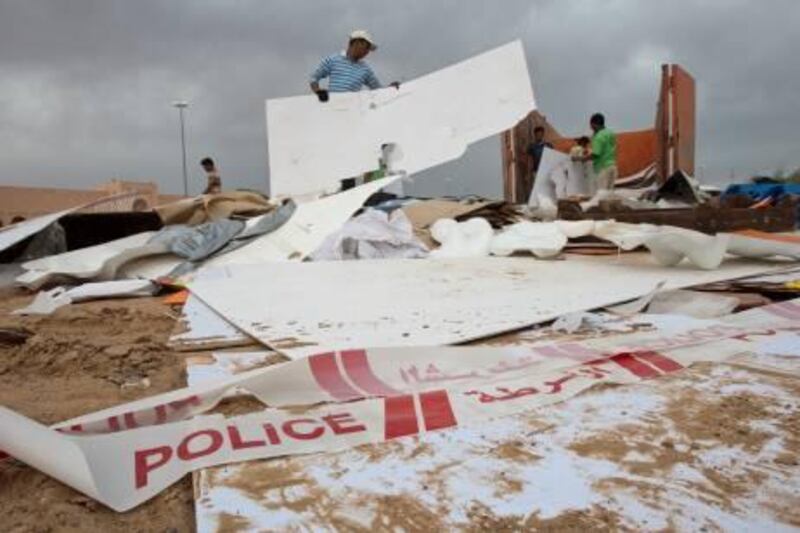 Police tape is left over as workers pick up the remains of Al Khaleej tent souk which fell due to high winds and heavy rain Sunday in Al Ain on Wednesday, April 13, 2011. Pawel Dwulit  /The National
