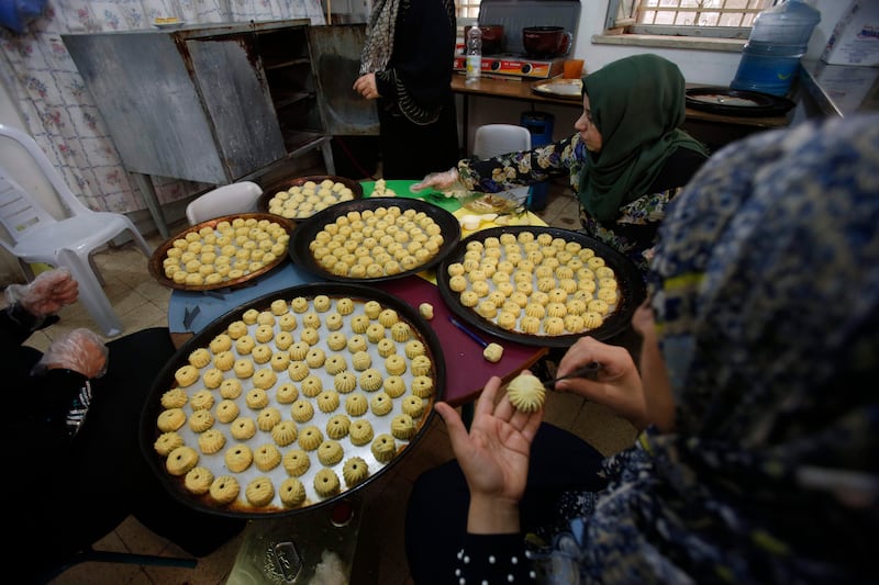 Palestinian women make traditional cookies filled with dates or nuts in preparation for the Eid al-Adha celebrations, on August 28, 2017, in the West Bank town of Hebron. / AFP PHOTO / HAZEM BADER