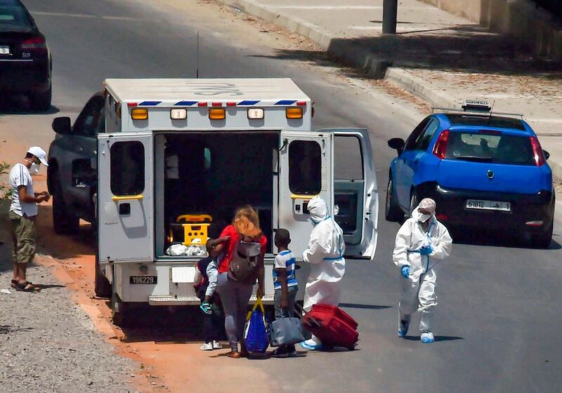 Moroccan medics help a woman and her children into an ambulance, after testing positive for the coronavirus, ahead of taking them into quarantine in the capital Rabat. AFP