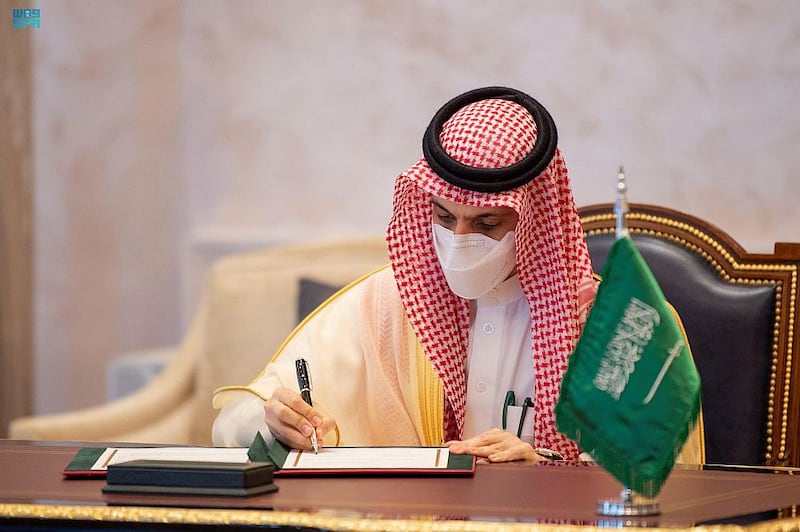 Saudi Foreign Minister Faisal bin Farhan signs an agreement.