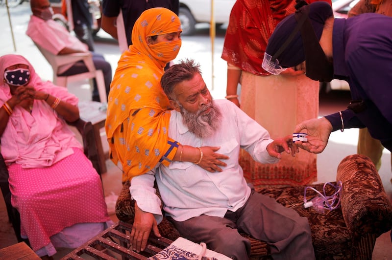 A volunteer uses a pulse oximeter to check the oxygen saturation of a man's blood before providing him oxygen support for free at a Gurudwara (Sikh temple), amidst the spread of coronavirus disease, in Ghaziabad, India. Reuters