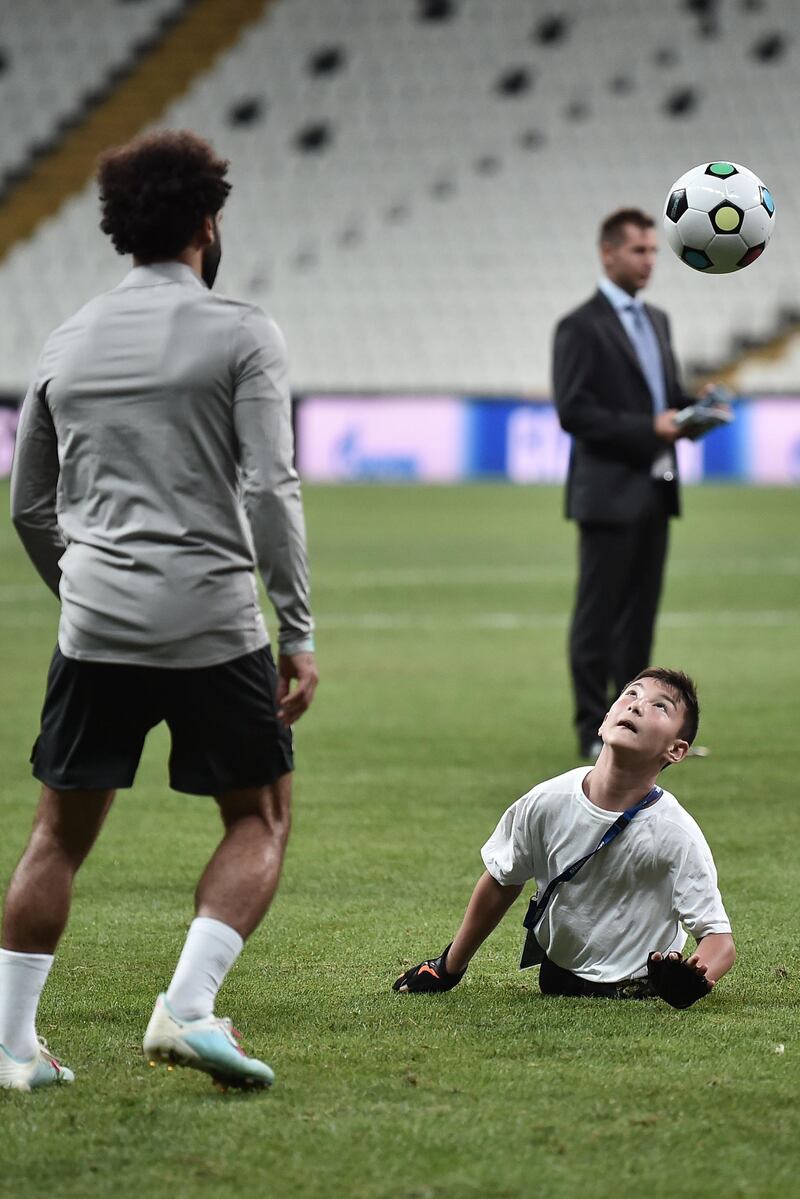 Liverpool's Egyptian midfielder Mohamed Salah plays football with a child at the end of a training session. AFP