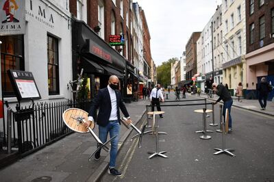 Employees place tables outside their restaurant in preparation for evening business, on Frith Street, Soho in the West End of London on October 16, 2020, as new restrictions on social gatherings and movement are set to come into force in London to combat the spread of the novel coronavirus COVID-19.  Roughly half of England is now under tougher coronavirus restrictions, after the government on October 15 announced more stringent measures for London and seven other areas to try to cut surging numbers of Covid-19 cases. / AFP / Ben STANSALL
