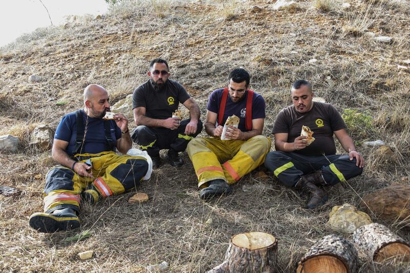 Exhausted civil defence volunteers take a break to eat after battling to control the fires for 24 hours.