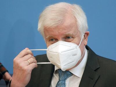 German Interior Minister Horst Seehofer removes his face mask before addressing a news conference on extremism in Berlin, Germany October 6, 2020. Wolfgang Kumm/Pool via Reuters