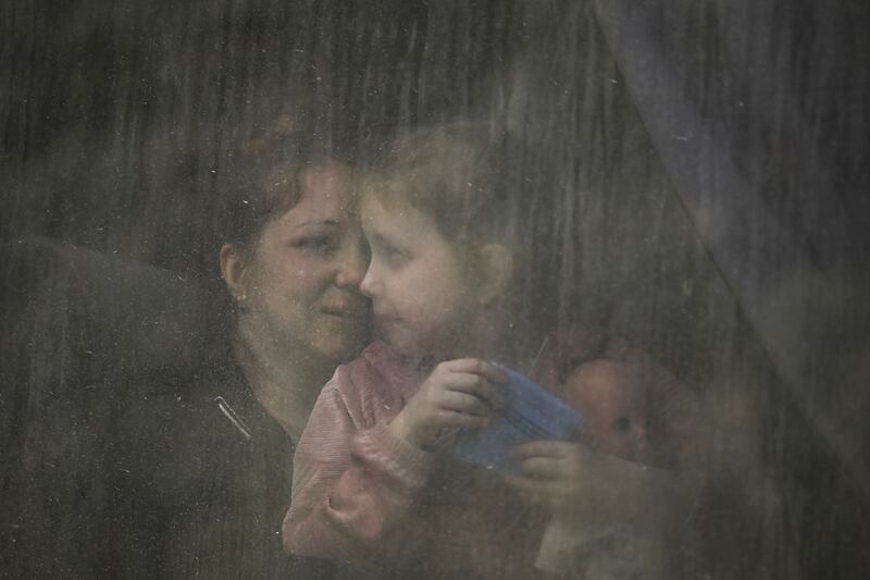 A mother with her daughter sit inside a bus as they leave Bakhmut. AFP