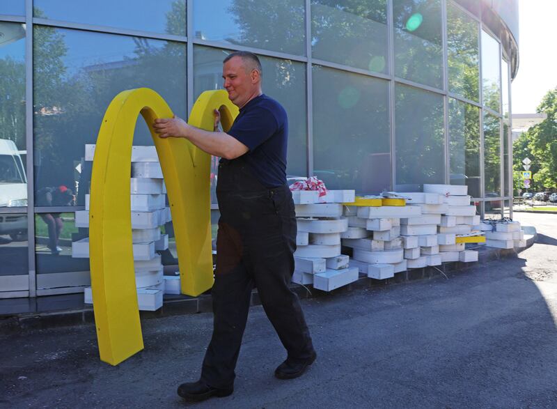 A worker carries dismantled McDonald's golden arches outside a restaurant in St Petersburg. Reuters