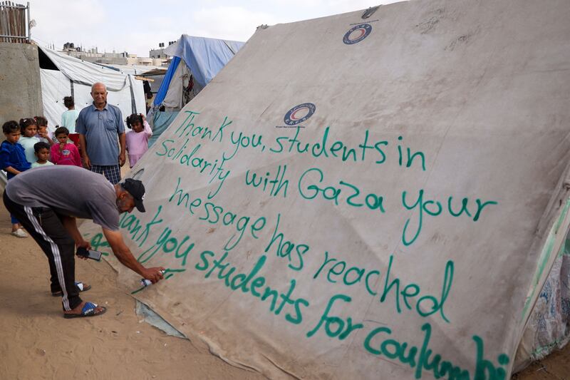 A man writes a message of thanks to students in the US protesting in solidarity with the people of Gaza, at a camp for displaced Palestinians in Rafah on April 27. AFP