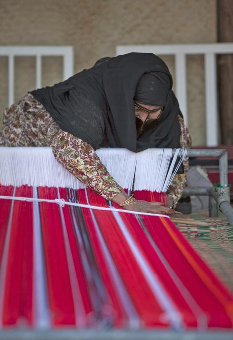 A lady weaves a traditional fabric at the Abu Dhabi Women’s Union stand. Silvia Razgova / The National