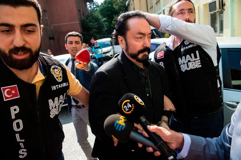 Turkish police officers escort televangelist and leader of a sect, Adnan Oktar (C) on July 11, 2018, in Istanbul, as he is detained on fraud charges.
 Turkish police detained the televangelist on fraud charges on July 11, 2018, notorious for propagating conservative views while surrounded by scantily-clad women he refers to as his "kittens". - Turkey OUT
 / AFP / DOGAN NEWS AGENCY / -
