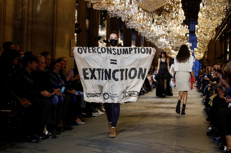 An Extinction Rebellion activist burst on to the catwalk with a banner that read: 'Overconsumption = Extinction' during Louis Vuitton's show at Paris Fashion Week. Reuters