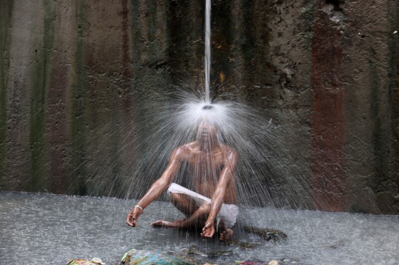 A man cools off under a pipe of flowing water on a hot summer day in New Delhi, India. Reuters