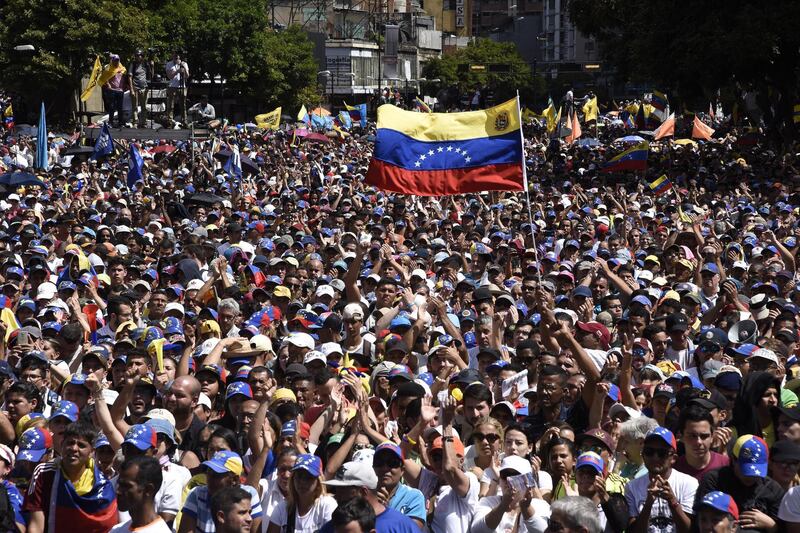 Demonstrators wave Venezuelan flags while listening to Juan Guaido, president of the National Assembly, not pictured, during a pro-opposition rally in Caracas, Venezuela, on Wednesday, Jan. 23, 2019. President Donald Trump recognized Guaido as the interim president of Venezuela minutes after the opposition leader declared himself the head of state, in the U.S.'s most provocative move yet against the leftist regime of President Nicolas Maduro. Photographer: Carlos Becerra/Bloomberg