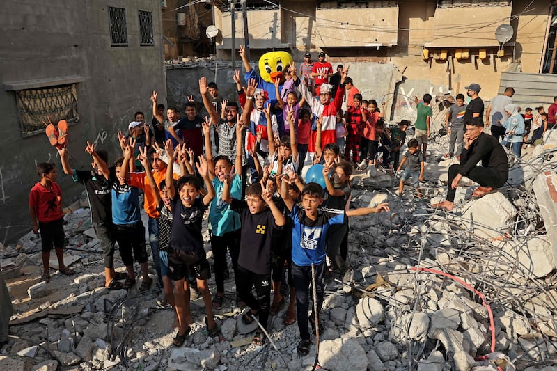 Palestinian children are entertained amid the rubble. AFP