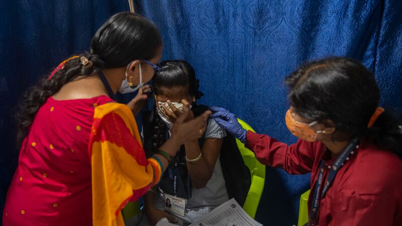A girl crying just after she received her Covid-19 shot in Mumbai is comforted. India has begun vaccinating those aged 15 to 18. AP