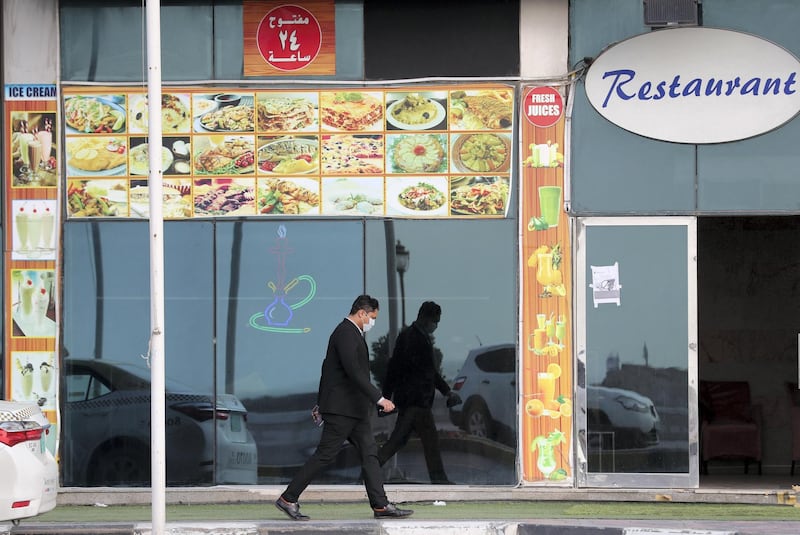 Ajman, United Arab Emirates - Reporter: N/A: A man with a face mask walks passed a restaurant in Ajman. Monday, March 23rd, 2020. Ajman. Chris Whiteoak / The National