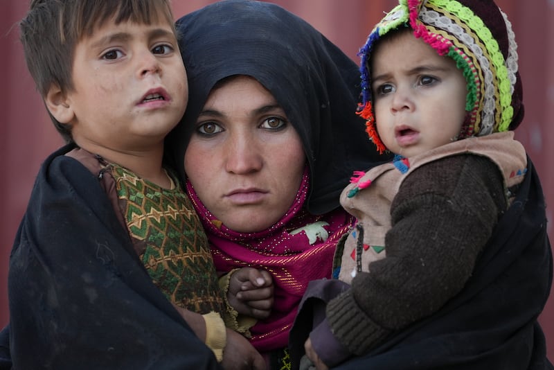 An Afghan woman with her children outside a makeshift clinic at a sprawling settlement of mud brick huts housing those displaced by war and drought near Herat. AP Photo