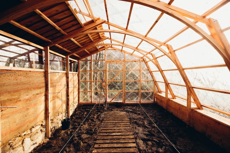 The wall performs as a thermal insulator for the greenhouse, absorbing heat during the day and releasing it at night