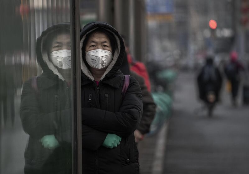 A Chinese woman wears a protective mask as she waits for a bus in Beijing, China. Getty Images