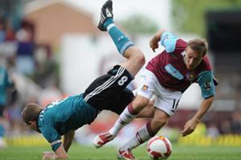 The Liverpool captain Steven Gerrard falls over West Ham's Mark Noble as they battle for the ball at Upton Park. Gerrard's two goals helped the Reds to a 3-0 win which took them back to the top of the Premier League.