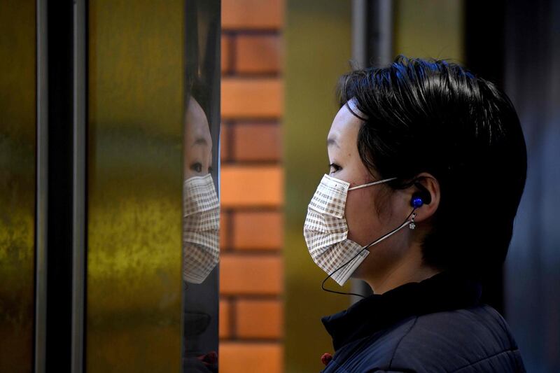 A woman wearing a protective facemask looks on in Yu Park in Shanghai. AFP