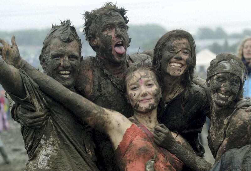 SOMERSET, ENGLAND - JUNE 26:  Festival-goers dance in the mud in front of the Pyramid stage at Worthy Farm, Pilton, Somerset, at the 2004 Glastonbury Festival, 26 June 2004. The festival spans over 3 days and runs until June 27.  (Photo by Matt Cardy/Getty Images)