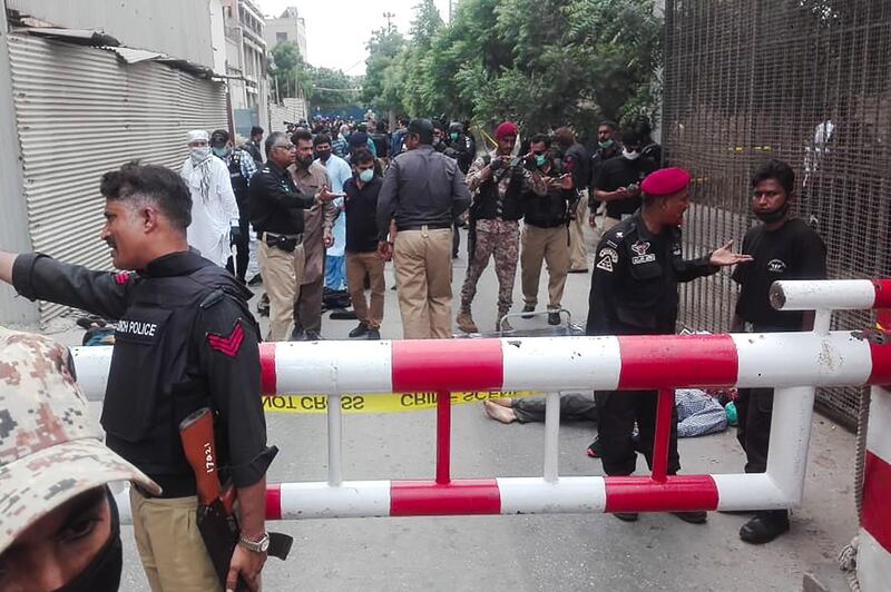 TOPSHOT - Policemen secure an area around a body outside the Pakistan Stock Exchange building after a group of gunmen attacked the building in Karachi on June 29, 2020. A group of gunmen attacked the Pakistan Stock Exchange in Karachi June 29, police said, with four of the attackers killed. / AFP / Asif HASSAN
