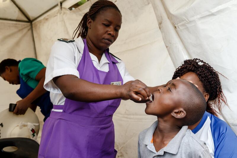 A Zimbabwean medical staff gives a young boy a vaccine against cholera during a vaccination campaign on October 5, 2018, following a deadly outbreak of the disease in the country's capital Harare. (Photo by Jekesai NJIKIZANA / AFP)